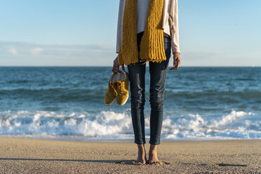 Barfüßige Frau am Strand, die ihre Schuhe trägt - AFVF02122