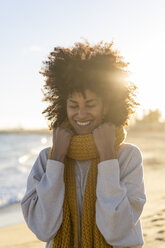 Porträt einer glücklichen Frau am Strand, die einen gelben Schal trägt - AFVF02126