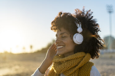 Woman with yellow scarf, listening music on the beach - AFVF02137