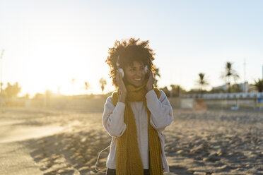 Woman with yellow scarf, listening music on the beach - AFVF02140