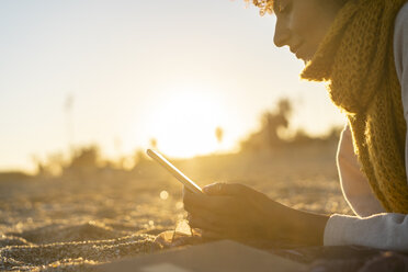 Frau liegt im Sand, entspannt sich am Strand und liest ein E-Book - AFVF02154