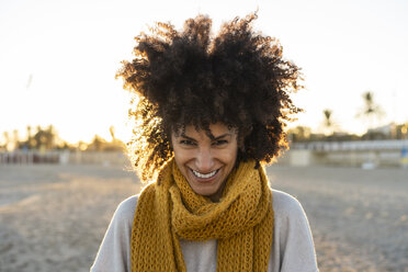 Porträt einer glücklichen Frau am Strand, die einen gelben Schal trägt - AFVF02165