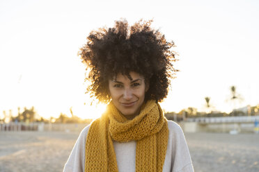 Porträt einer glücklichen Frau am Strand, die einen gelben Schal trägt - AFVF02166