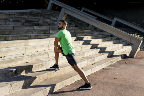 Sportive man during workout, stretching on steps - MAUF01959