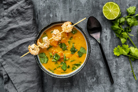 Bowl of sweet potato soup with shrimps, coconut flakes and fresh coriander stock photo
