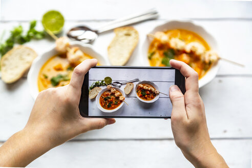 Mädchen fotografiert Schalen mit Süßkartoffelsuppe mit Smartphone, Nahaufnahme - SARF04024