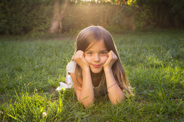 Portrait of little girl lying on a meadow at evening twilight - LVF07609