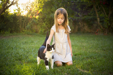 Porträt eines kleinen Mädchens, das eine Katze im Garten streichelt - LVF07612