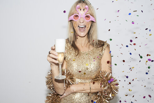 Senior woman wearing golden dress and flmingo shaped glasses, celebtraing New Year's Eve - IGGF00692