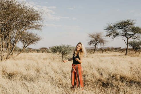 Afrika, Namibia, blonde lächelnde Frau im Grasland stehend - LHPF00223