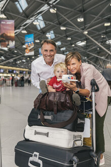 Porträt einer glücklichen Familie mit Gepäckwagen auf dem Flughafen - MFF04716