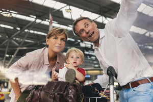 Glückliche Familie mit Gepäckwagen auf dem Flughafen - MFF04719