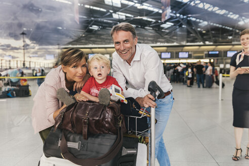 Porträt einer glücklichen Familie mit Gepäckwagen auf dem Flughafen - MFF04720