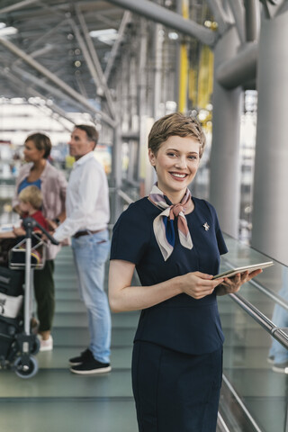 Porträt eines lächelnden Mitarbeiters einer Fluggesellschaft mit einem Tablet am Flughafen, lizenzfreies Stockfoto