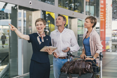 Angestellter einer Fluggesellschaft, der einem Paar am Flughafen mit dem Gepäckwagen hilft - MFF04727