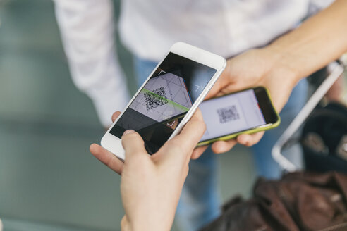 Mitarbeiter einer Fluggesellschaft scannt QR-Codes von Passagieren mit dem Smartphone am Flughafen - MFF04729