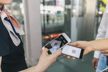 Mitarbeiter einer Fluggesellschaft scannt QR-Codes von Passagieren mit dem Smartphone am Flughafen - MFF04730