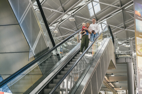 Glückliche Familie auf der Rolltreppe am Flughafen, lizenzfreies Stockfoto