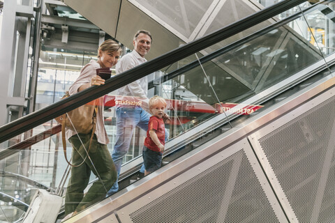 Glückliche Familie auf der Rolltreppe am Flughafen, lizenzfreies Stockfoto