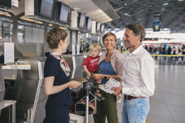 Happy family with airline employee at the airport check-in - MFF04747