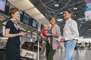 Happy family with airline employee at the airport check-in - MFF04748