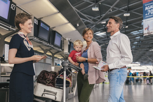Glückliche Familie mit Mitarbeiter der Fluggesellschaft beim Check-in am Flughafen - MFF04748