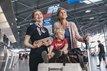 Glücklicher Mitarbeiter einer Fluggesellschaft mit Mutter und Kind am Flughafen - MFF04753