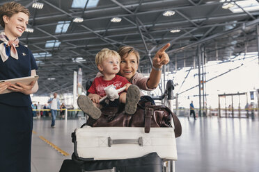 Eine reisende Mutter, die ihr kleines Kind auf dem Flughafen herumführt - MFF04754