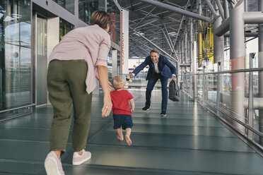 Glückliches Kind, das einem reisenden Geschäftsmann am Flughafen in die Arme läuft - MFF04755