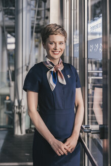 Porträt eines lächelnden Angestellten einer Fluggesellschaft, der am Fenster des Flughafens steht - MFF04760