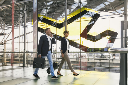 Geschäftsmann am Handy und Geschäftsfrau beim Spaziergang auf dem Flughafen - MFF04765