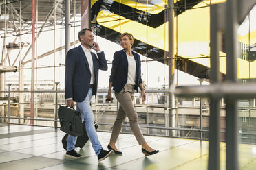Businessman on cell phone and businesswoman walking at the airport - MFF04766