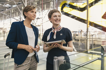 Lächelnder Mitarbeiter einer Fluggesellschaft mit Tablet und Geschäftsfrau auf dem Flughafen - MFF04767