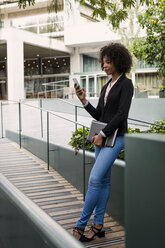 Smiling businesswoman looking at cell phone outdoors - MAUF01998