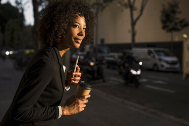 Porträt einer Geschäftsfrau mit Kaffee zum Mitnehmen und Mobiltelefon in der Abenddämmerung - MAUF02000