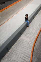 Geschäftsfrau am Telefon sitzend an der Wand - MAUF02008