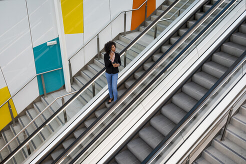 Geschäftsfrau am Telefon stehend auf Rolltreppe - MAUF02011
