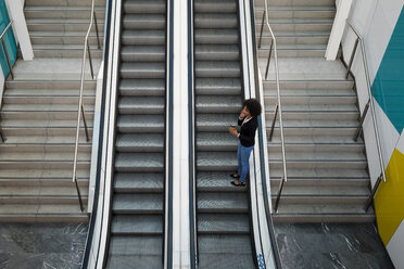 Geschäftsfrau am Telefon stehend auf Rolltreppe - MAUF02012