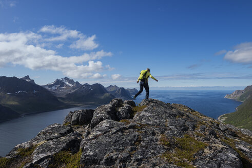 Wanderin auf dem Gipfel des Riven mit dem Oyfjord im Hintergrund, Senja, Troms, Norwegen - AURF07913