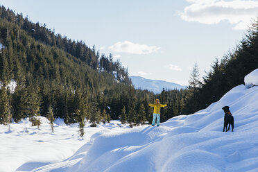 Frau spielt mit Hund im Winter, Whistler, British Columbia, Kanada - AURF08076