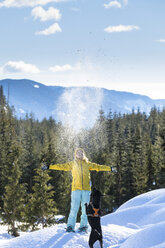 Woman playing with dog in winter, Whistler, British Columbia, Canada - AURF08077