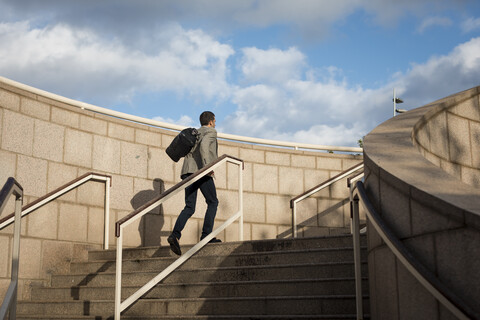 Geschäftsmann mit Tasche geht die Treppe hinauf, lizenzfreies Stockfoto