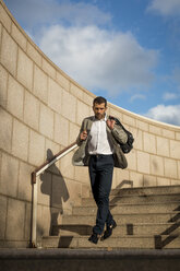 Businessman with bag walking downstairs - MAUF02033