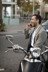 Happy businessman on motorscooter talking on cell phone - MAUF02042