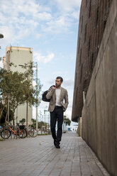 Businessman with bag walking in the city - MAUF02058