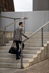Geschäftsmann mit Tasche, der eine Treppe in der Stadt hinaufgeht - MAUF02059