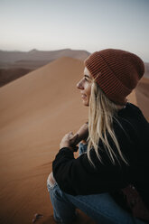 Namibia, Namib desert, Namib-Naukluft National Park, Sossusvlei, smiling woman sitting on Dune 45 at sunrise - LHPF00238