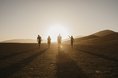 Namibia, Namib-Wüste, Namib-Naukluft-Nationalpark, Sossusvlei, Freunde wandern an der Düne 45 bei Sonnenaufgang, lizenzfreies Stockfoto