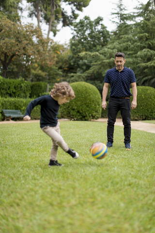 Vater und Sohn spielen Fußball im Park, lizenzfreies Stockfoto