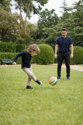 Father and son playing football in park - MAUF02080